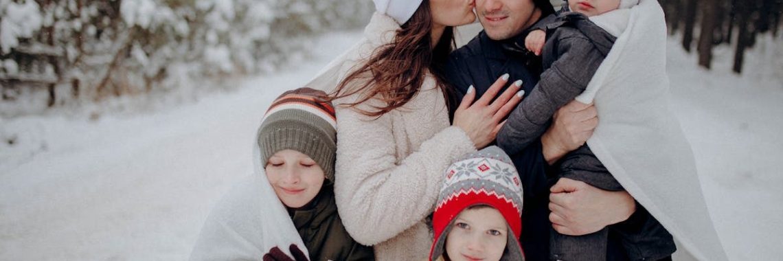 A joyful family enjoying a snowy day in a forest, wrapped in warm clothing.